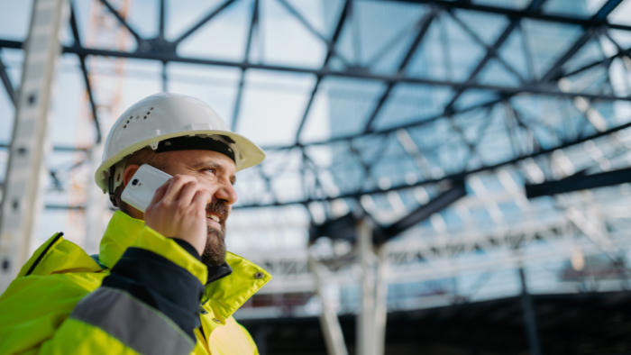 A man holds a cell phone at a construction jobsite