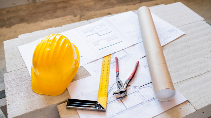 A yellow hard hat on top of construction plans at a construction jobsite