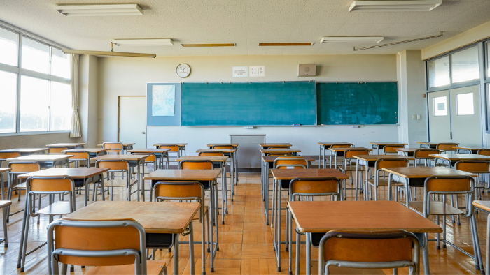 Classroom with desks sit in front of a blackboard