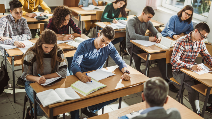 Students in a classroom write on paper