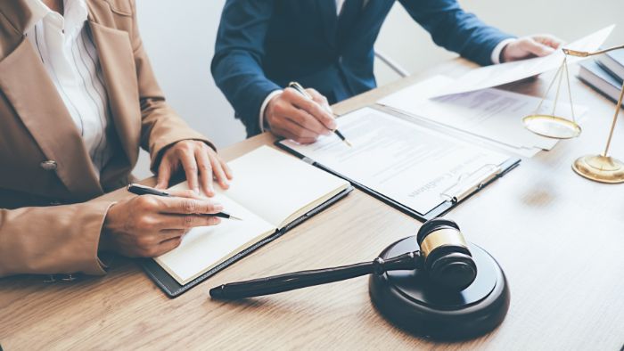 Lawyers sit at a table with a gavel