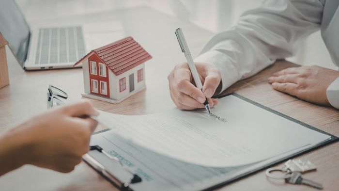 A person signs a document at a title company closing table
