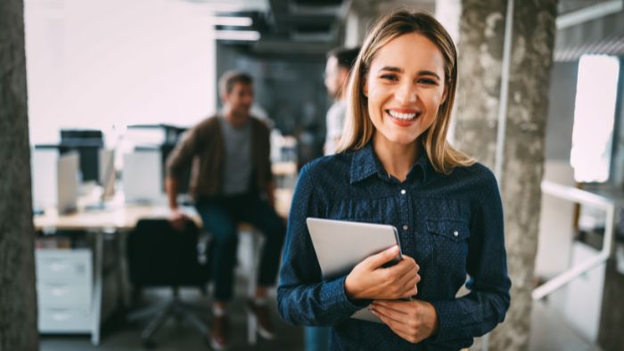 A woman is smiling and welcoming a client into an office